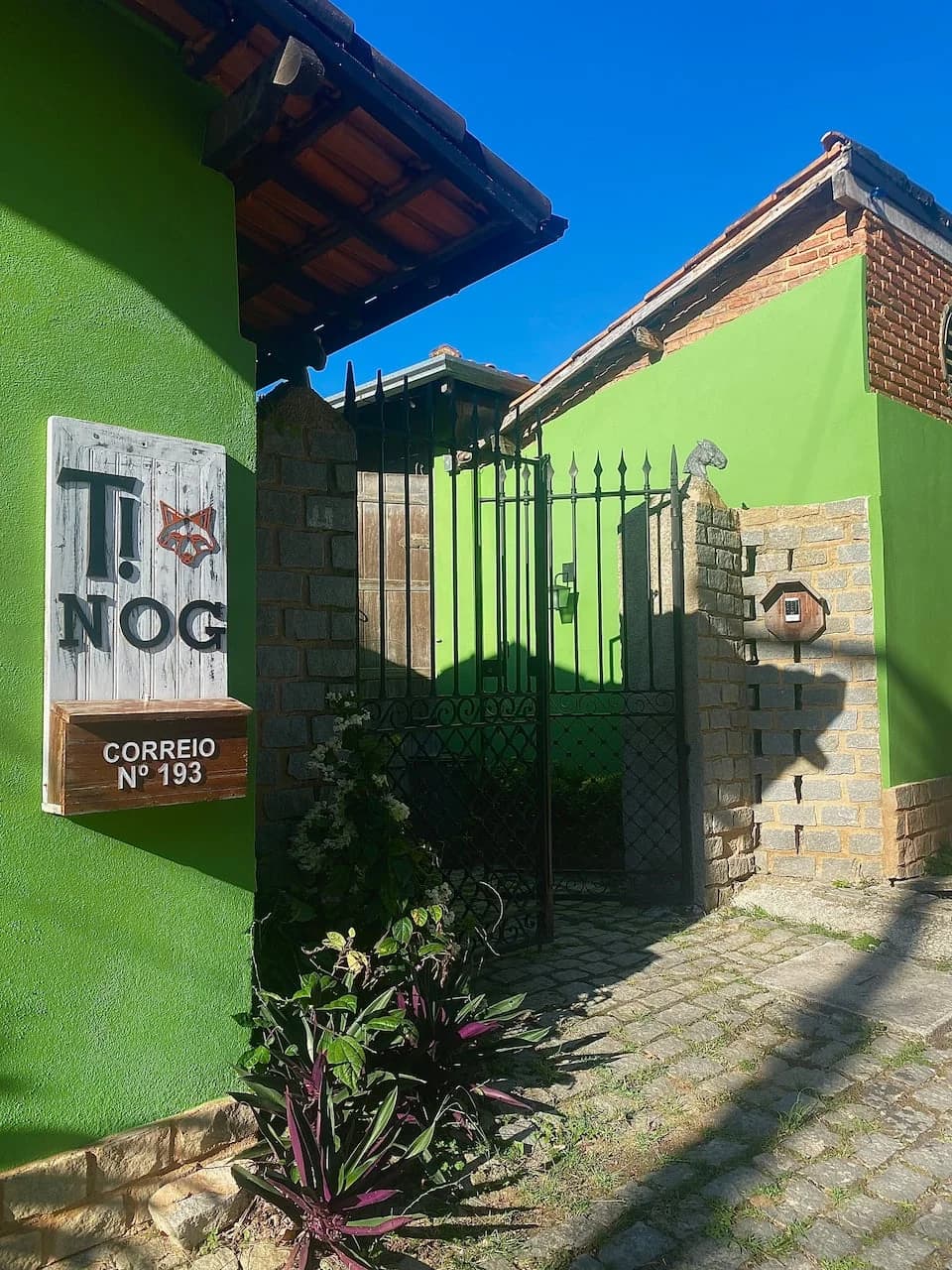 A entrada da Tinog Lofts: parede verde, a placa pintada à mão com o logo da raposa e o portão de ferro